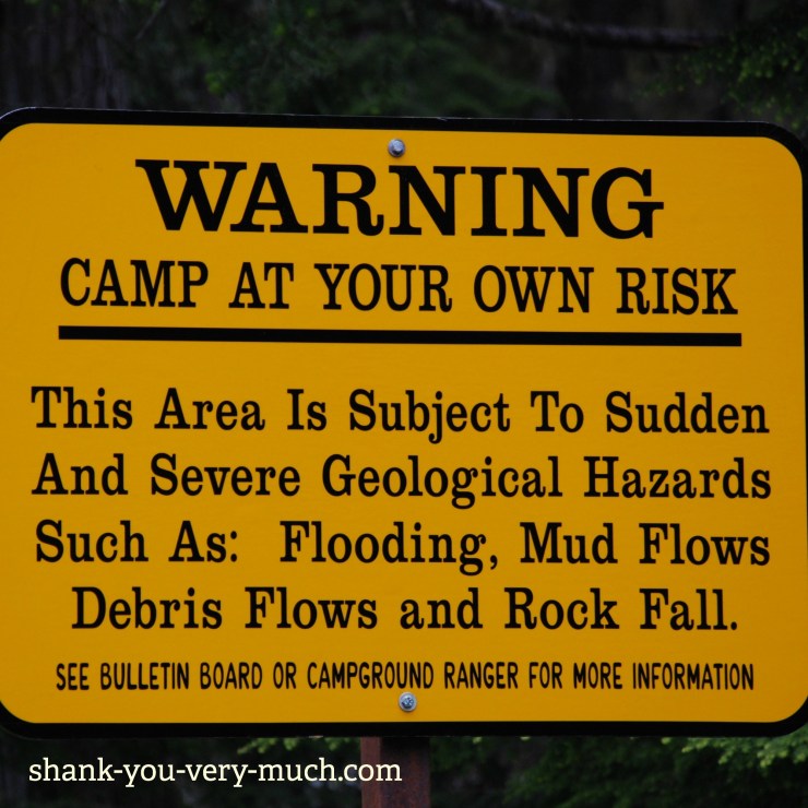 A warning sign that says " Camp at your own risk. This area is subject to sudden and severe geological hazards such as: flooding, mud flows, debris flows and rock fall."